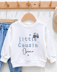 A white sweatshirt with blue text and a tractor graphic, hanging on a wooden hanger.