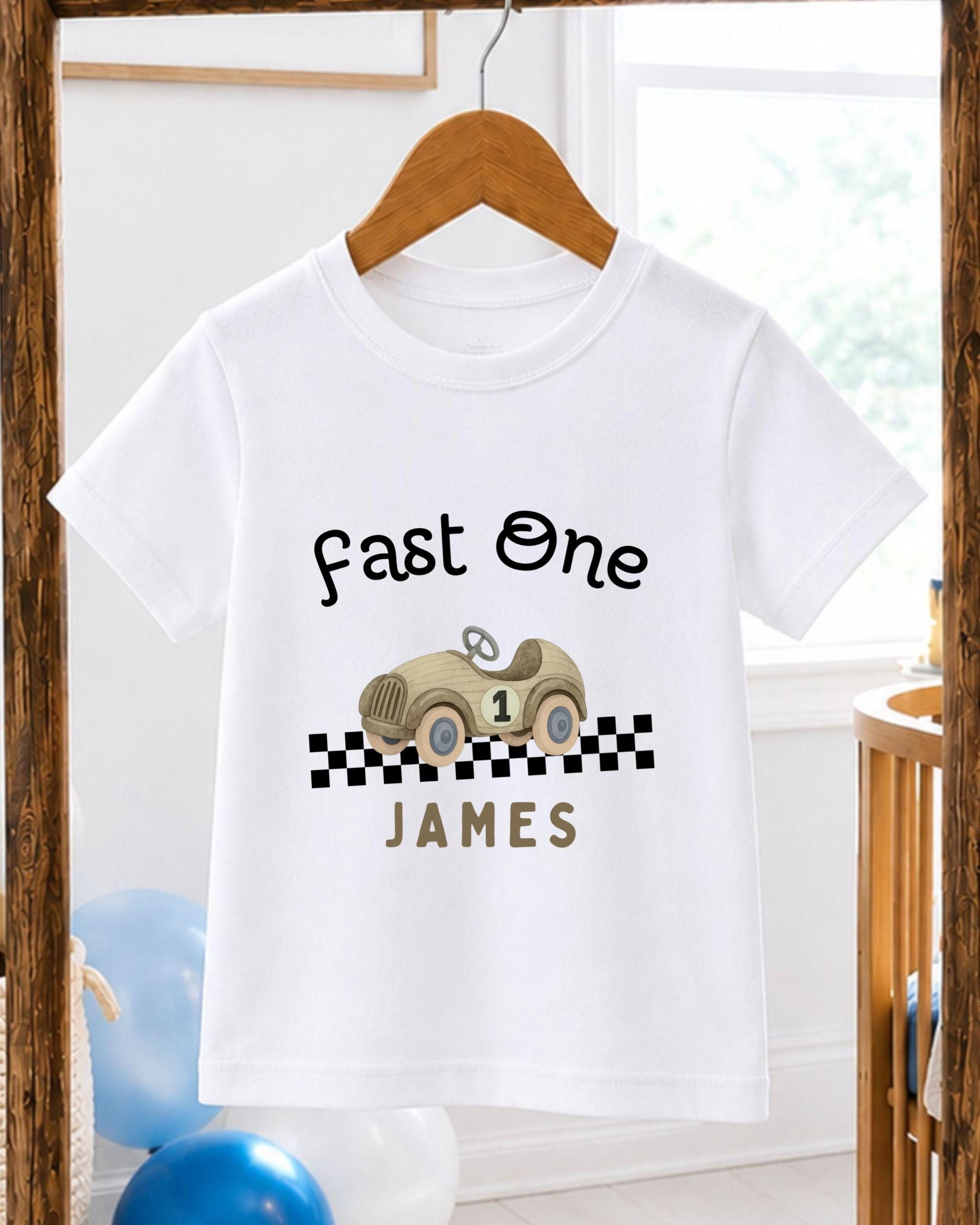 A white t-shirt with a graphic design of a race car and the text "Fast One James" printed on it.