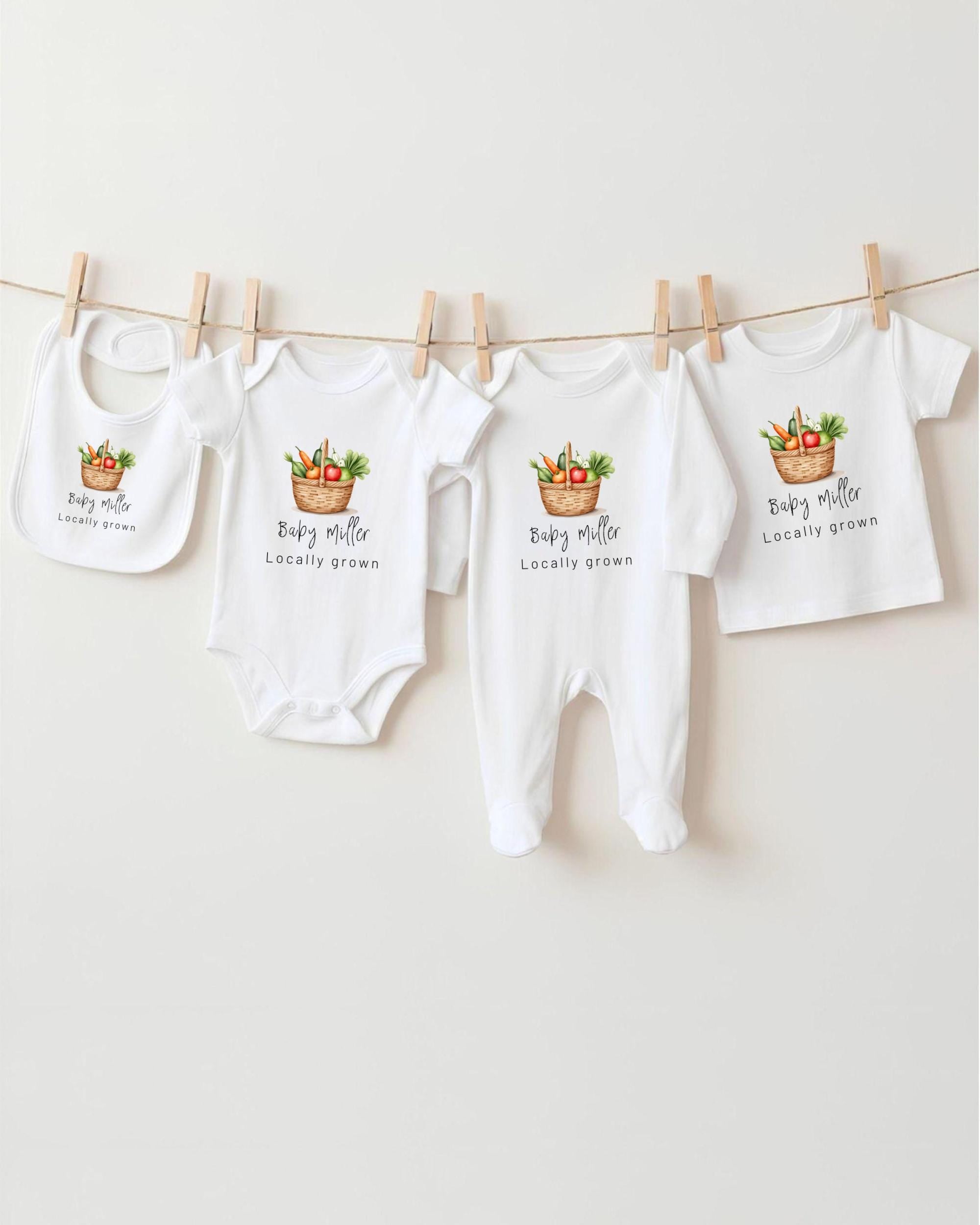 A row of four white baby clothes with the text "Baby Miller Locally grown" printed on them, hanging on a clothesline.