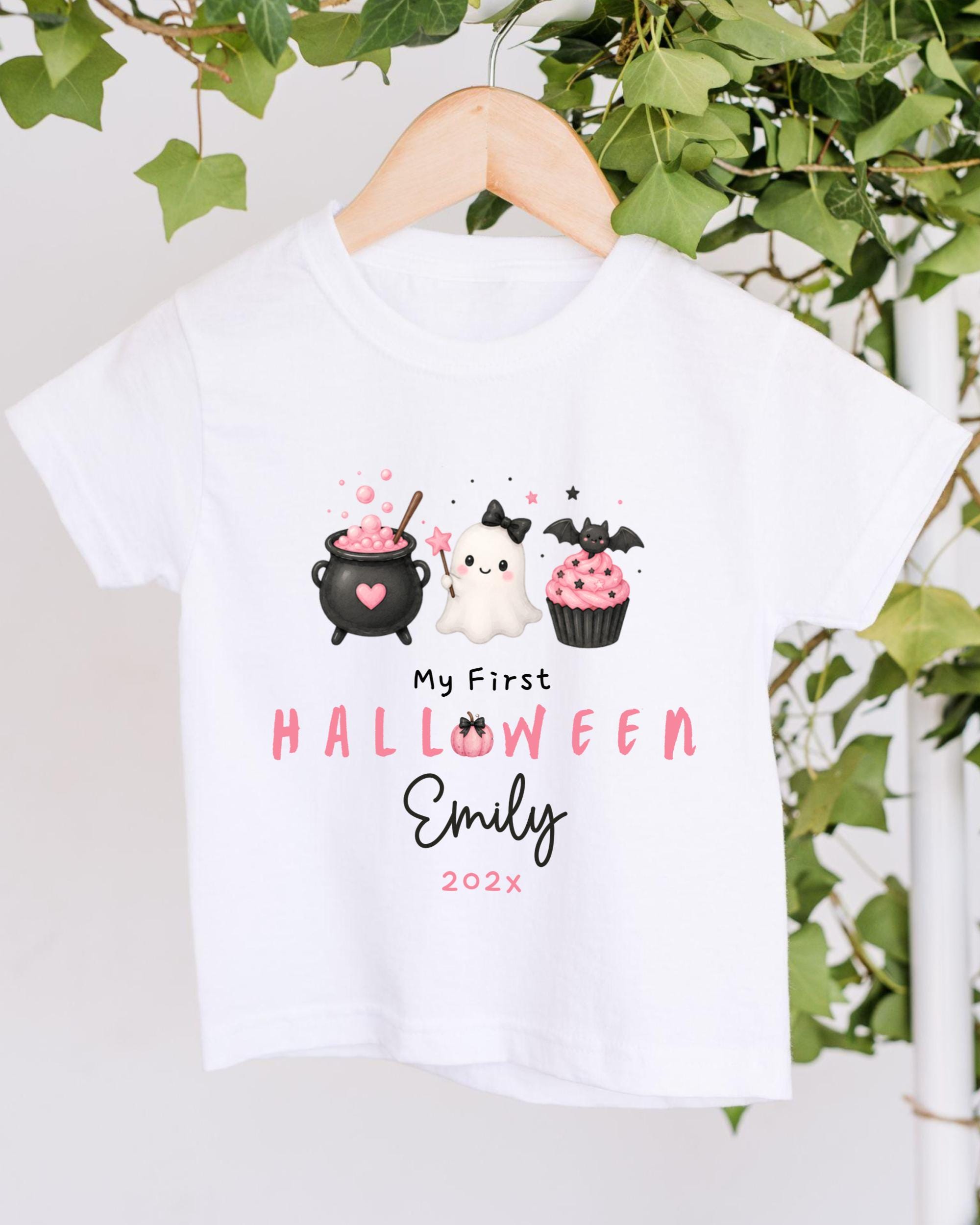 A white t-shirt with a Halloween-themed graphic design hanging on a wooden hanger.