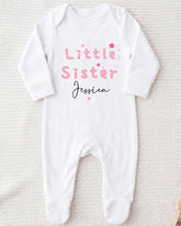 A white onesie with the text "Little Sister Jessica" printed on it.