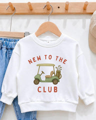 A white sweatshirt with a graphic of a golf cart and the text "NEW TO THE CLUB" printed on it, hanging on a wooden hanger.