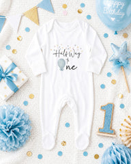 a baby onesie with the text "Half Way to One" printed on it, surrounded by various baby-themed items such as a blue balloon, a blue and gold polka dot gift box, a blue and gold star, a blue and gold confetti, a blue and gold pom pom, and a blue and gold number one.