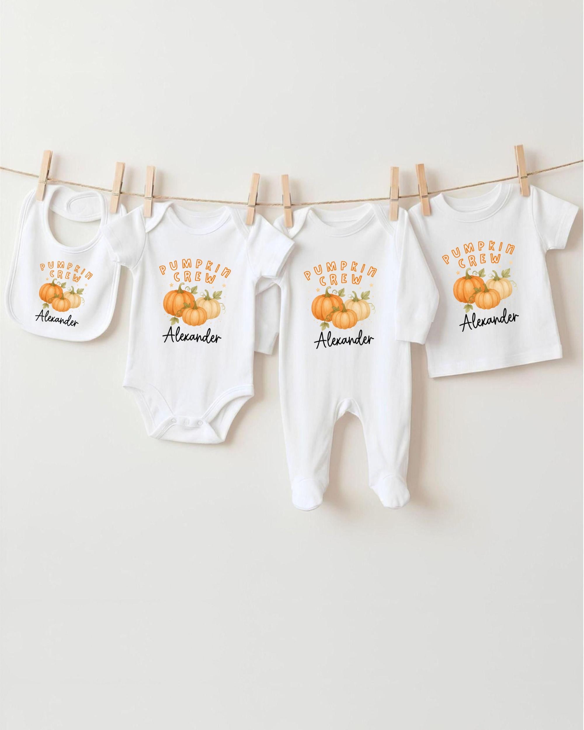 a collection of white baby clothes, including onesies and booties, hanging on a clothesline. The clothes feature a pumpkin theme, with the text "Pumpkin Crew Alexander" printed on them.