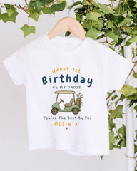 A white t-shirt with a golf cart graphic and text printed on it, hanging on a wooden hanger.