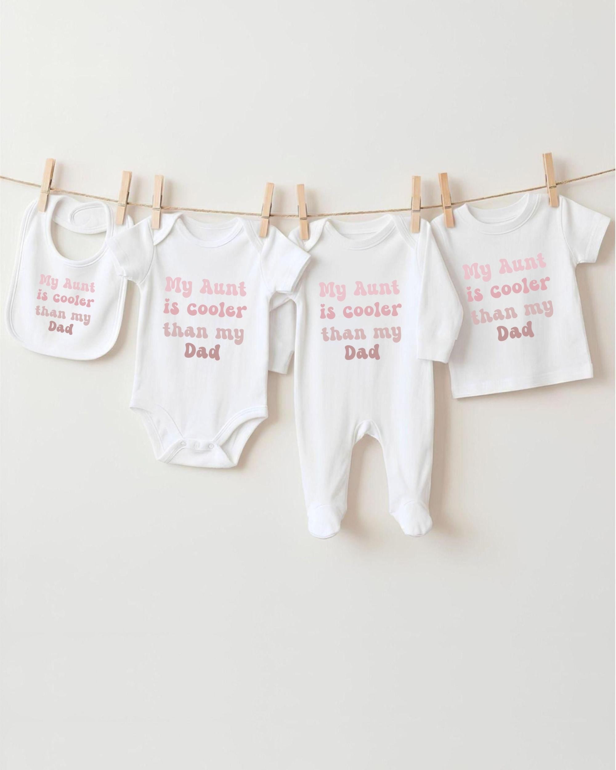a collection of baby clothes and bibs hanging on a clothesline, each with a different message printed on them.
