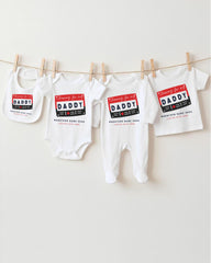 a collection of baby clothes, including onesies and bibs, hanging on a clothesline.
