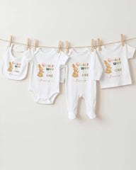 A collection of baby clothes, including onesies and bibs, hanging on a clothesline.