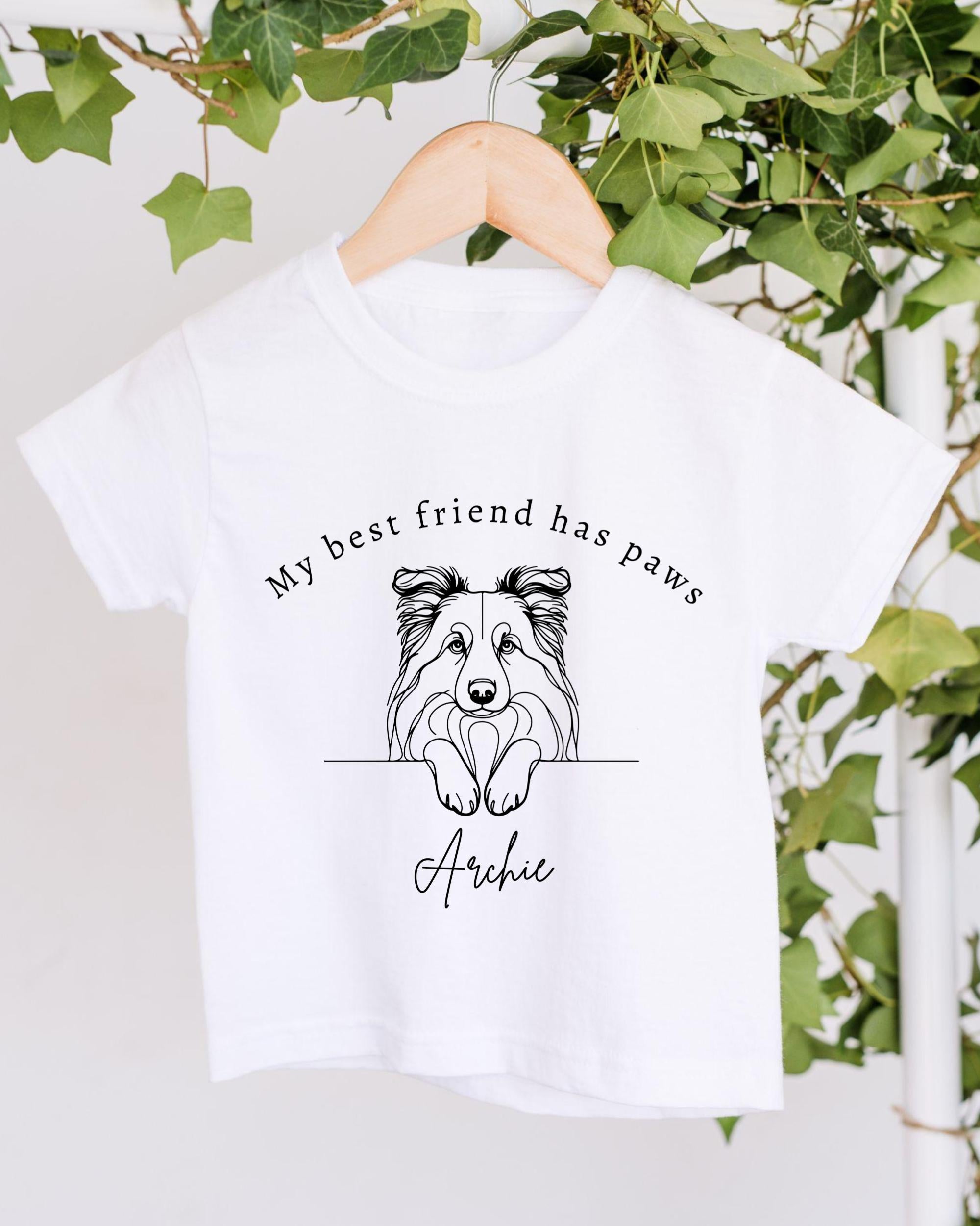 A white t-shirt with a black and white illustration of a dog's face and the text "My best friend has paws Archie" printed on it.