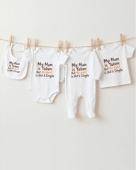 a collection of four white baby clothes hanging on a clothesline, each with a unique message printed on it.
