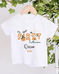 A white t-shirt with a Halloween-themed design hanging on a wooden hanger.