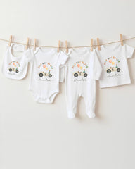 A collection of white baby clothes, including onesies and bibs, hanging on a clothesline.