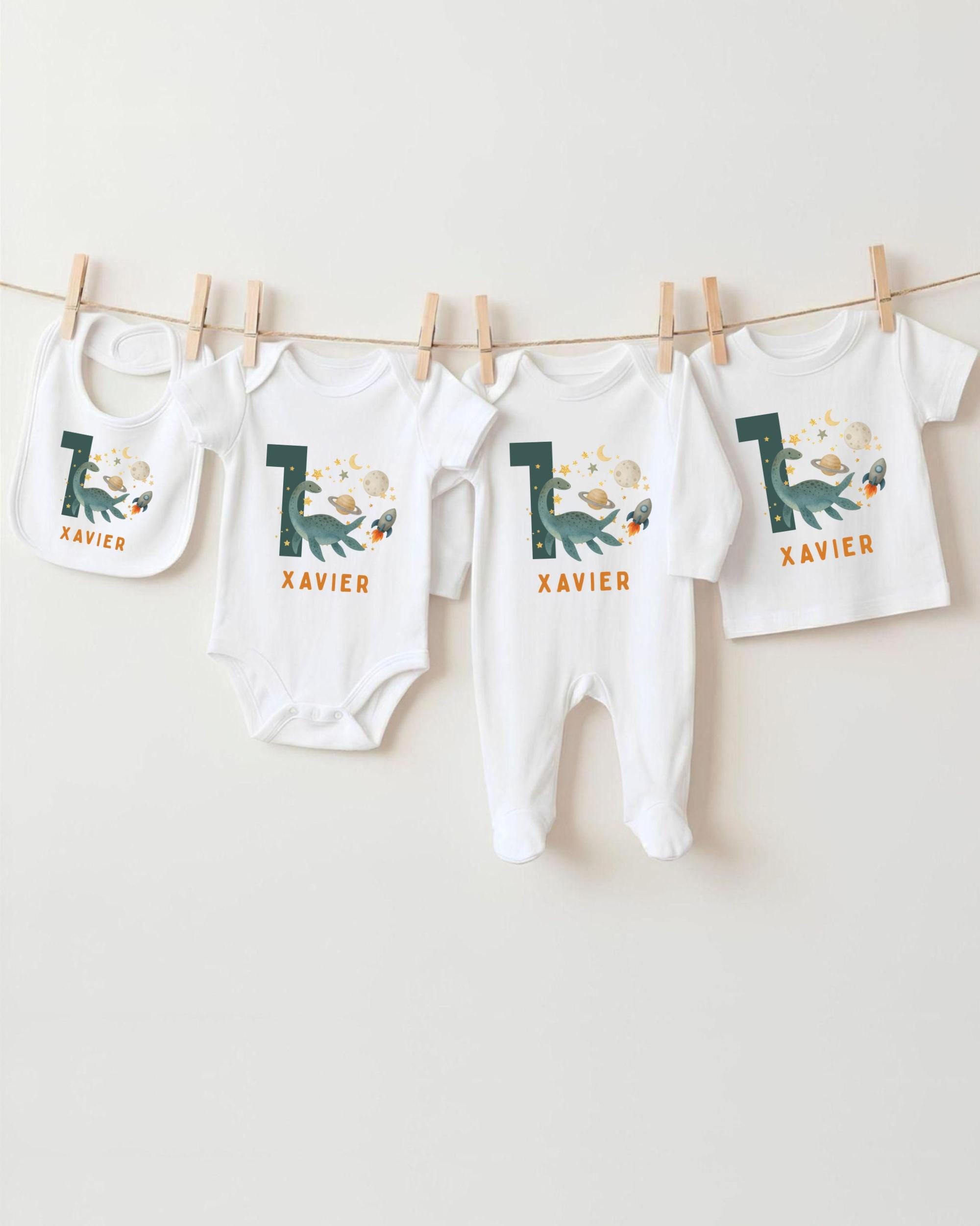 A collection of baby clothes, including onesies and bibs, hanging on a clothesline.