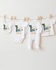 A collection of baby clothes, including onesies and bibs, hanging on a clothesline.