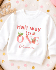 A white sweatshirt with a personalized message printed on it, placed on a surface with confetti.