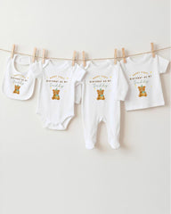 A collection of baby clothes, including onesies and bibs, hanging on a clothesline.