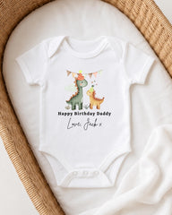 A white onesie with a dinosaur design and text that reads "Happy Birthday Daddy Love Jack x" is displayed on a bed.