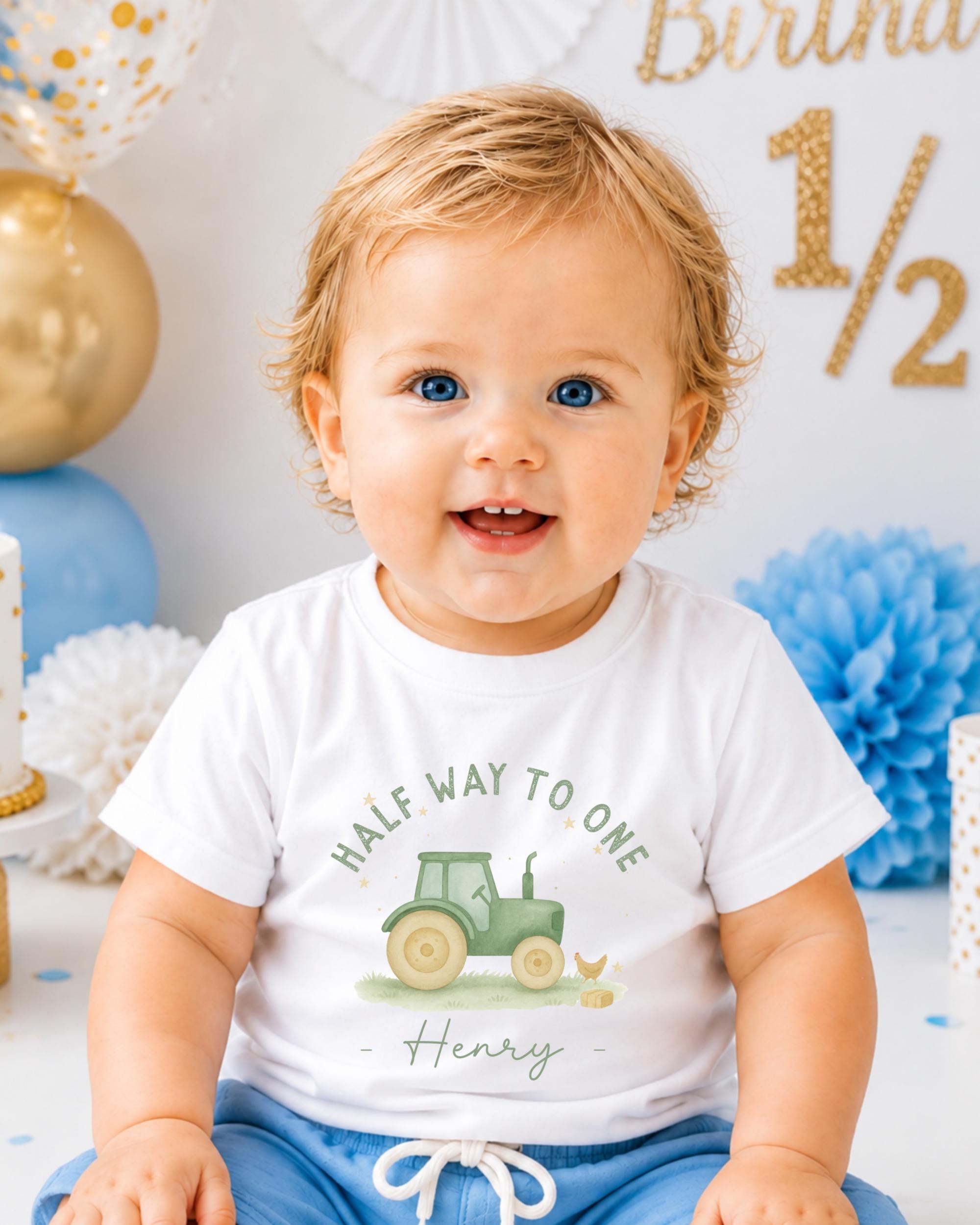 A smiling baby boy wearing a white t-shirt with a tractor graphic and the text "Half Way to One Henry" is sitting in front of a birthday party backdrop.
