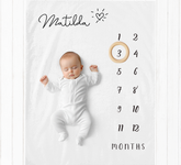 a baby laying on a blanket next to a clock
