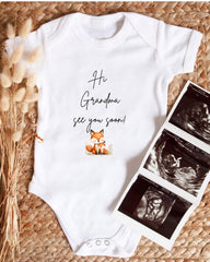 A white baby onesie with a fox graphic and the text "Hi Grandma, see you soon!" is displayed alongside a set of three black and white ultrasound images.