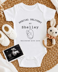 A white baby onesie with text, a crocheted bunny toy, and a black and white photograph of an infant's belly.