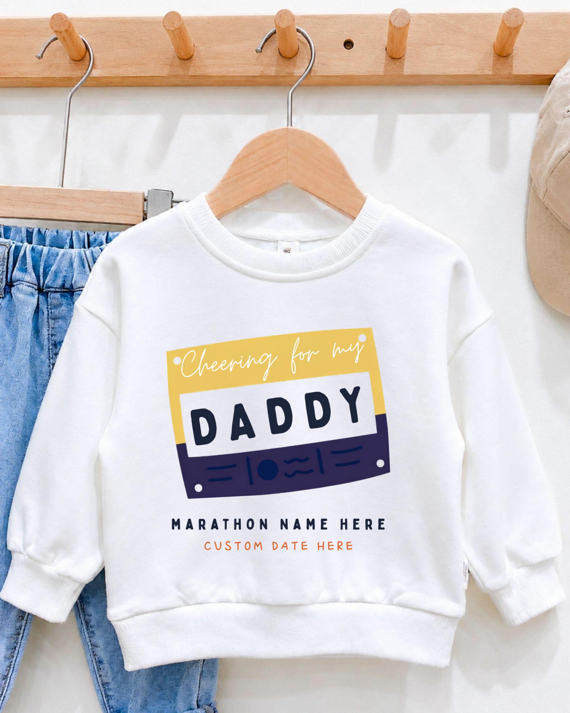 A white sweatshirt with a colorful graphic design and text, hanging on a wooden hanger.