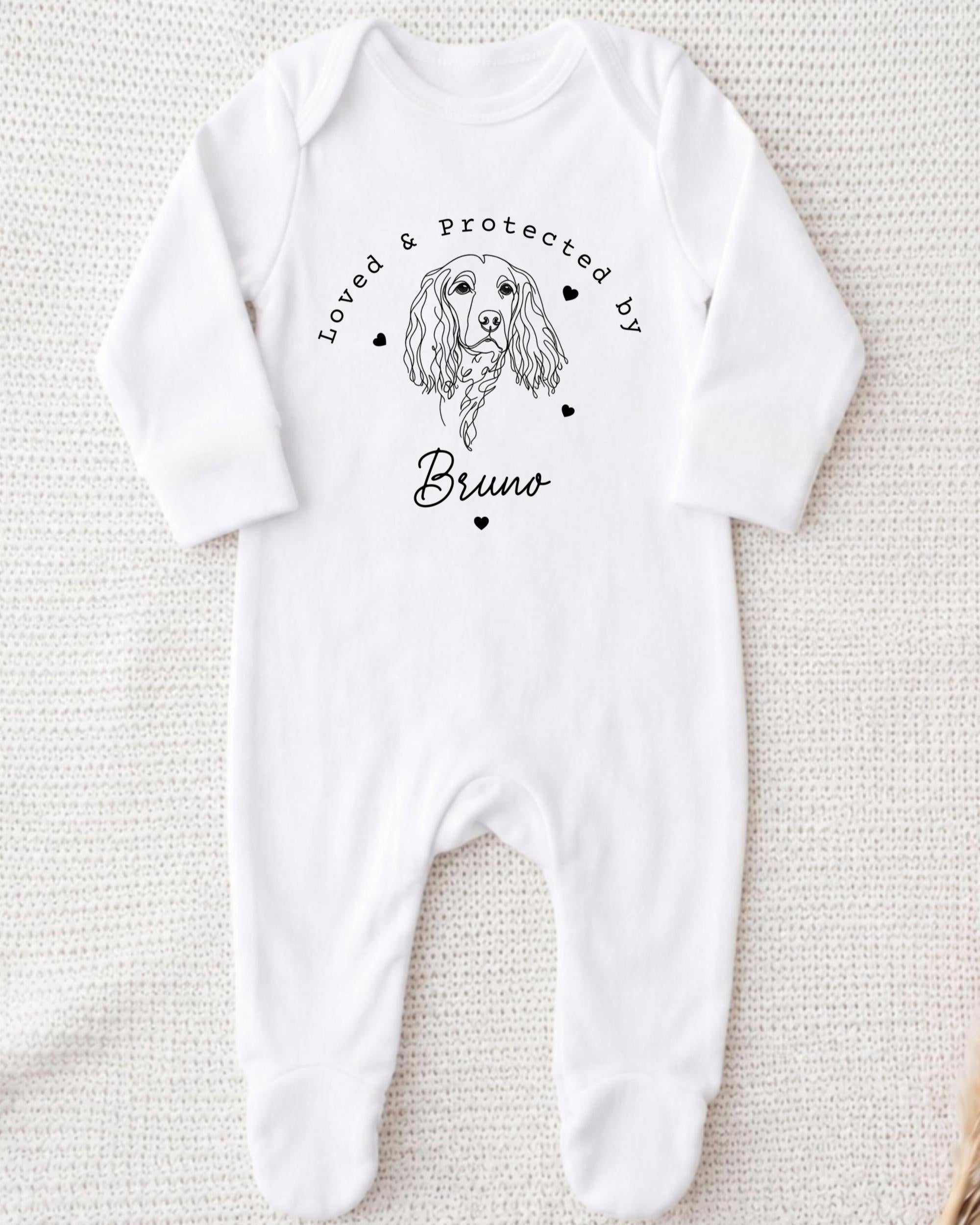 A white onesie with a black illustration of a dog and the text "Loved & Protected by Bruno" printed on it.