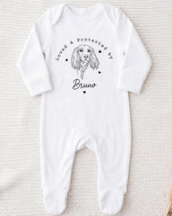 A white onesie with a black illustration of a dog and the text "Loved & Protected by Bruno" printed on it.