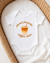 A white onesie with a graphic of a coffee cup and the text "Mama's favourite coffee date" printed on it, placed on a white blanket.
