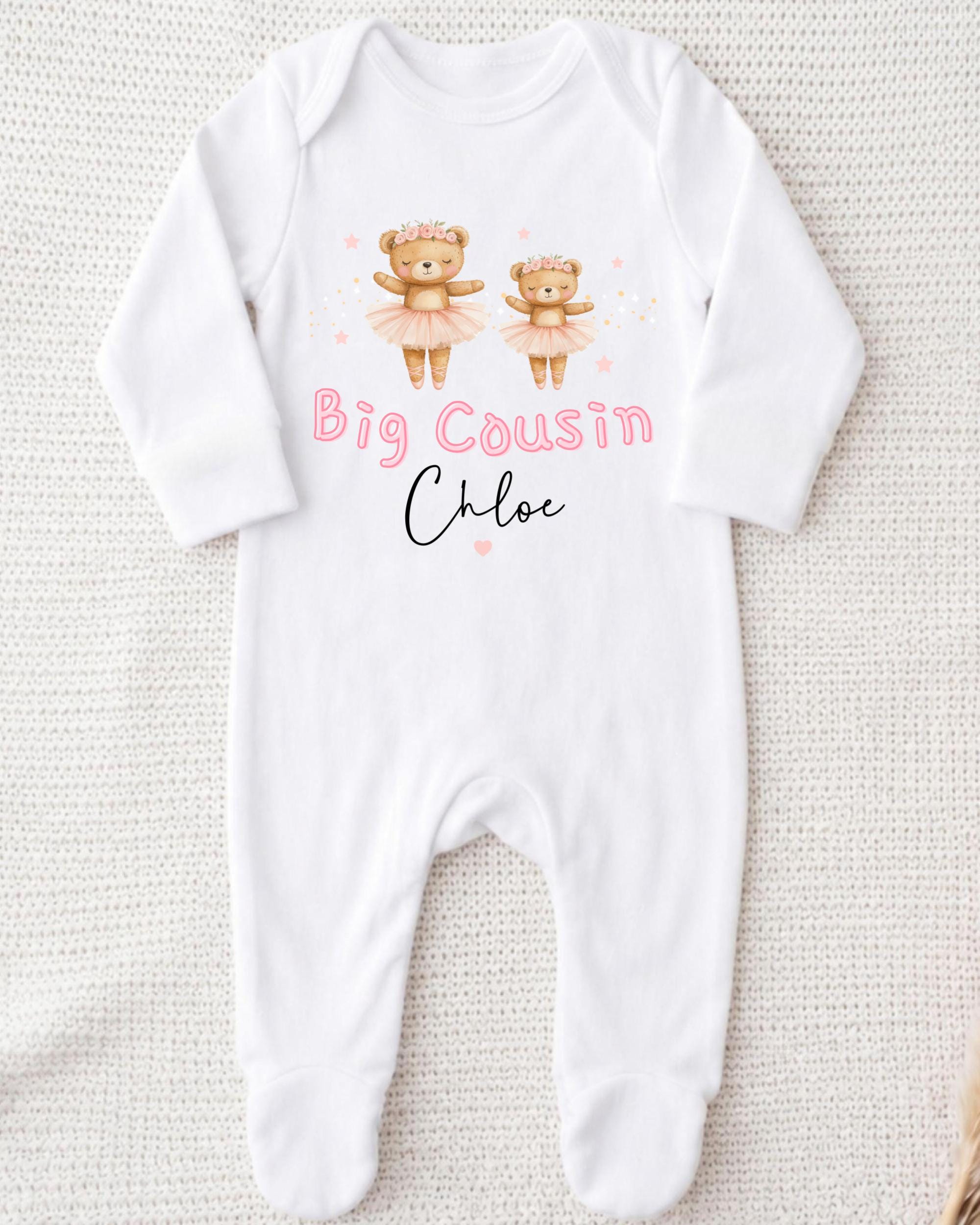 A white onesie with a design of two teddy bears in tutus and the text "Big Cousin Chloe" printed on it.