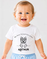 A smiling baby boy wearing a white t-shirt with a graphic of a dog and the text "My best friend has paws" and "ARTHUR" printed on it.