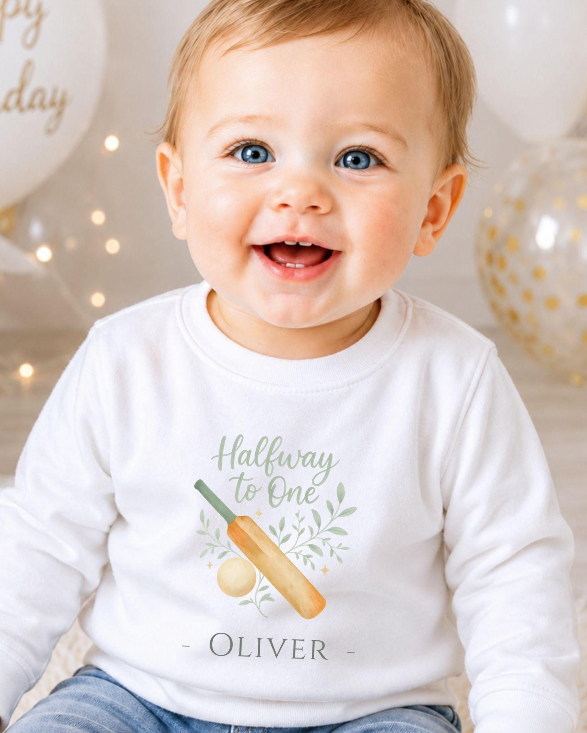 A smiling baby boy wearing a white shirt with a graphic and text printed on it.