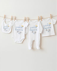 A row of four white baby clothes, including onesies and pajamas, hanging on a clothesline.