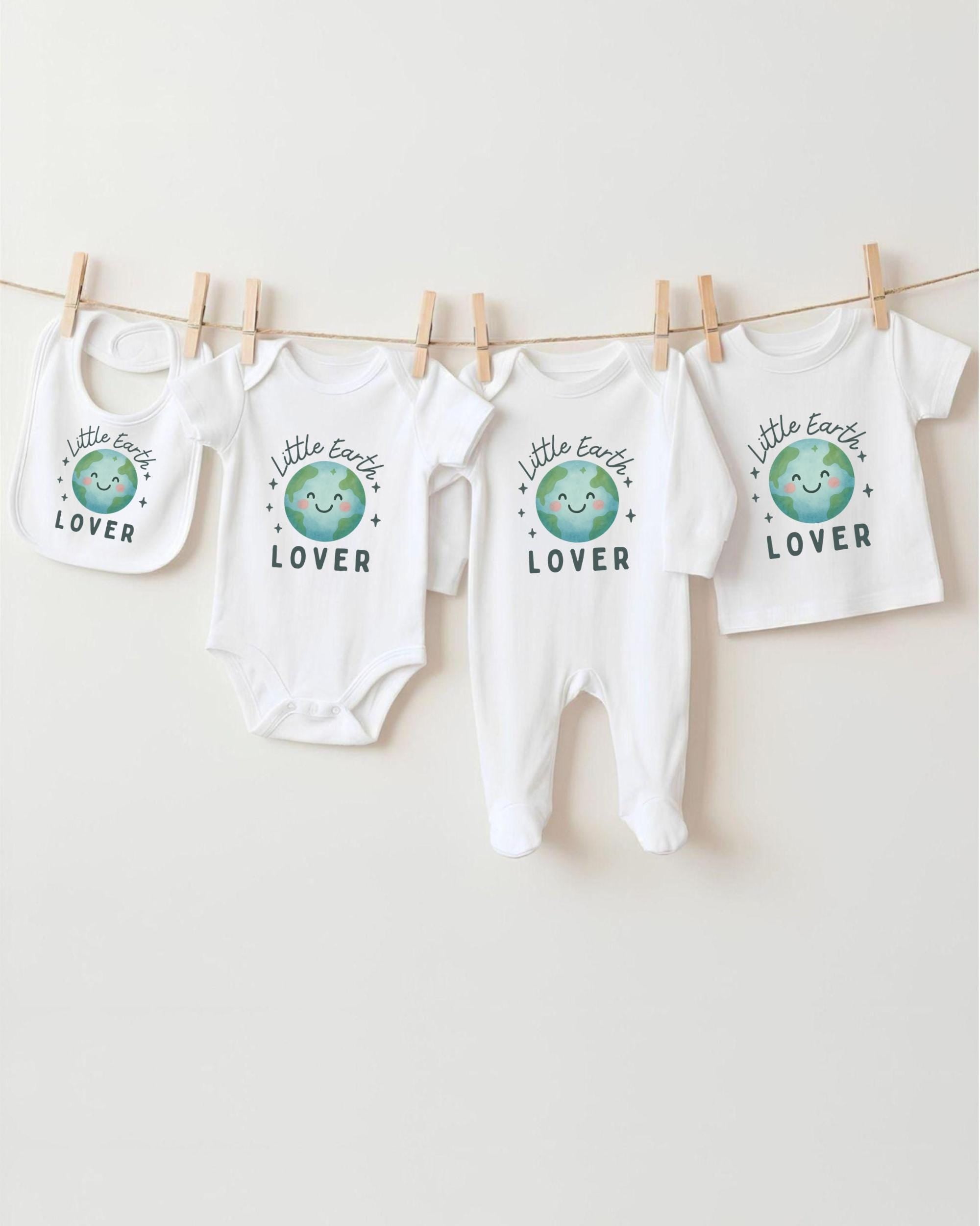 A collection of baby clothes, including onesies and bibs, hanging on a clothesline.