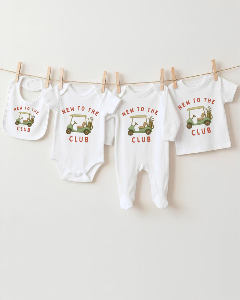 A row of four white baby clothes with the text "NEW TO THE CLUB" printed on them, along with a golf cart graphic.