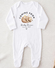 A white onesie with a graphic of a sleeping bear and text that says "Coming soon Baby Queen Autumn 2027".