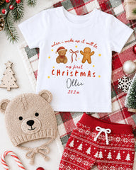 A white t-shirt with a Christmas-themed design, a beige knit hat, red and white patterned shorts, and other Christmas-themed items such as a gingerbread man and a snowflake ornament.