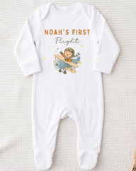 A white onesie with a cartoon airplane and the text "Noah's first flight" printed on it.