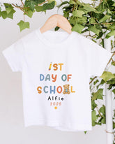 A white t-shirt with text and a teddy bear graphic, hanging on a wooden hanger.