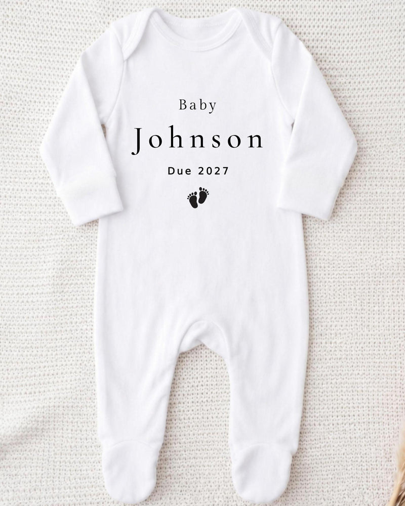 A white bodysuit with the text "Baby Johnson Due 2027" printed on it.