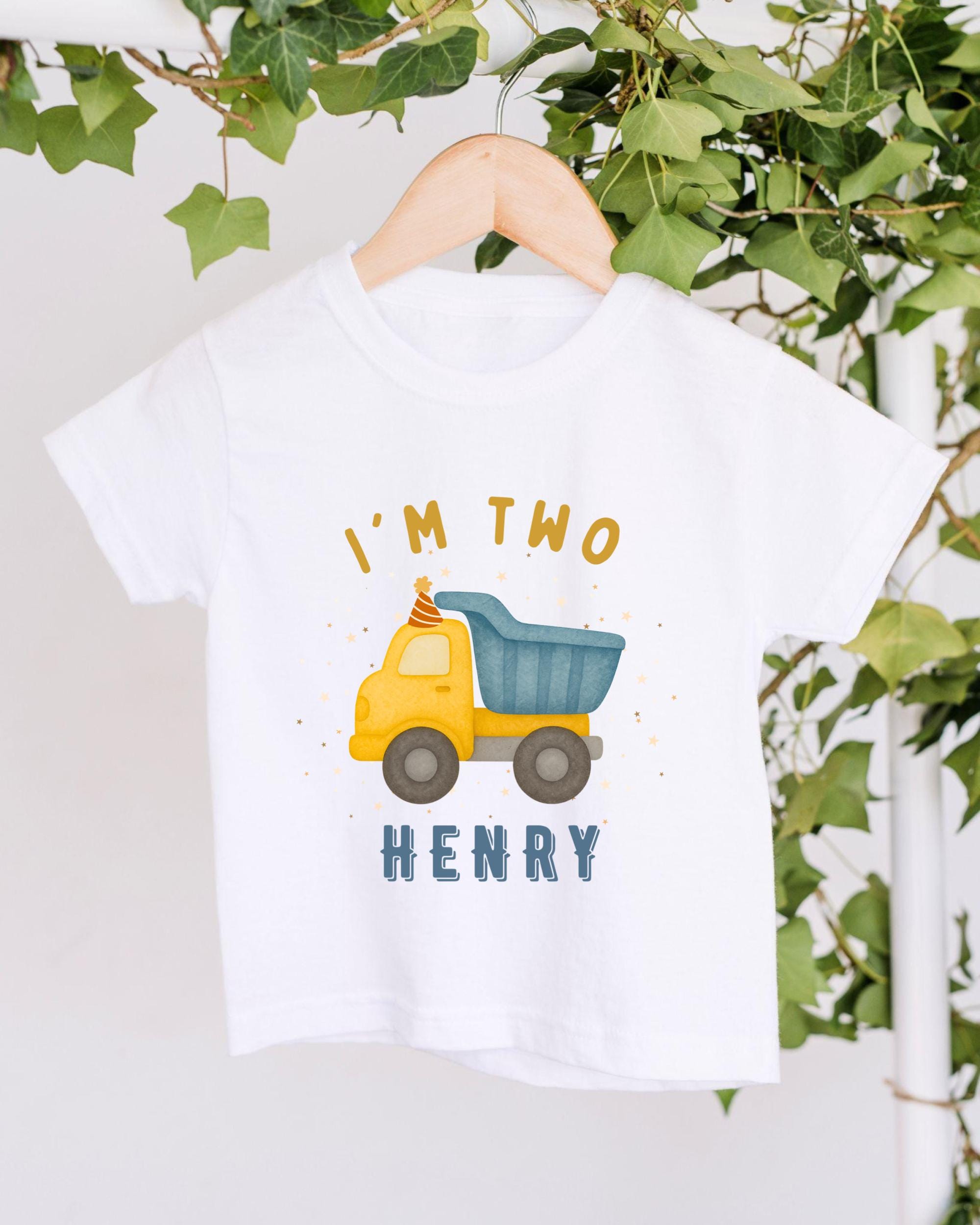 A white t-shirt with a graphic design of a yellow truck and the text "I'm two Henry" printed on it.