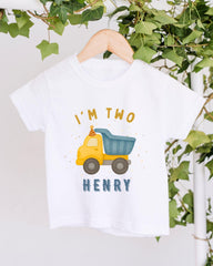 A white t-shirt with a graphic design of a yellow truck and the text "I'm two Henry" printed on it.