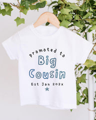 A white t-shirt with text printed on it, hanging on a wooden hanger.