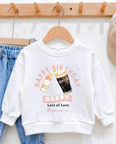 A white sweatshirt with a graphic design on it, featuring a bottle of milk and a glass of beer, along with the text "Happy Birthday Daddy Lots of Love Annie".