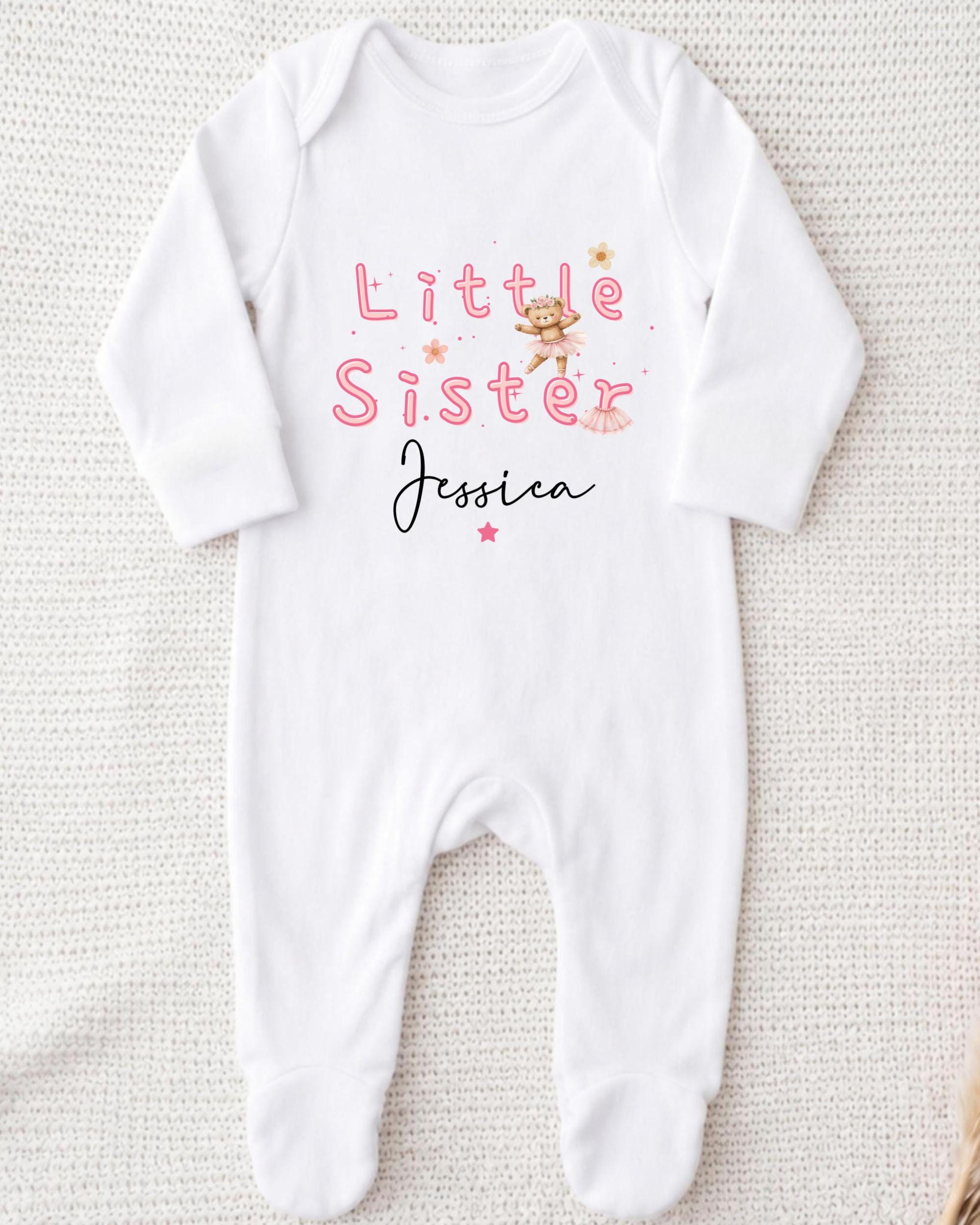 A white onesie with the text "Little Sister Jessica" printed on it.