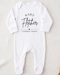 A white onesie with the text "BABY FETCHER COMING SOON" printed on it.
