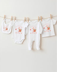 A collection of white baby clothes, including onesies and bibs, hanging on a clothesline.