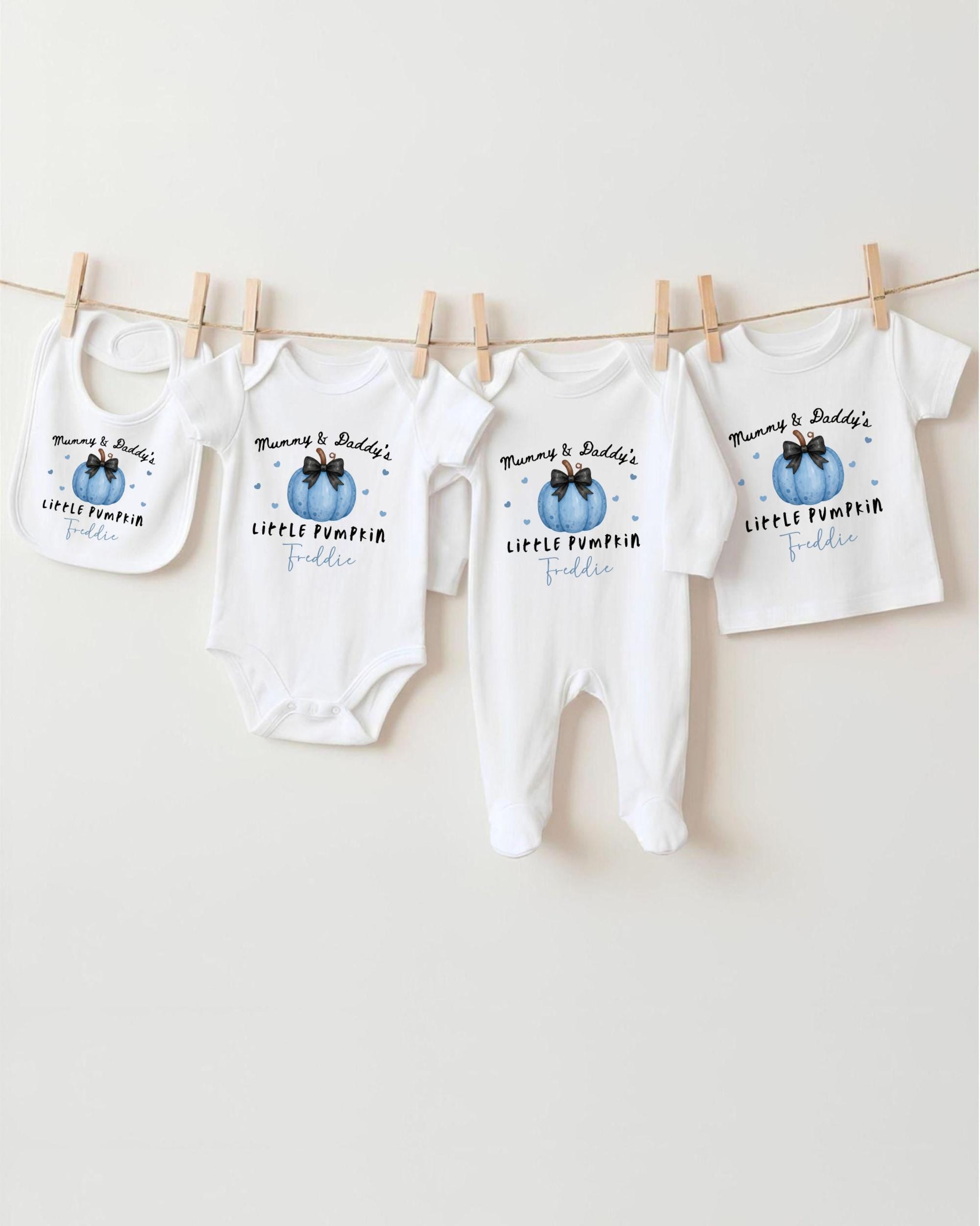A row of four white baby clothes with the text "Mum & Dad's LITTLE PUMPKIN FADDLE" printed on them, hanging on a clothesline.