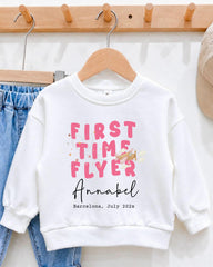 A white sweatshirt with pink text and a date printed on it, hanging on a wooden hanger.
