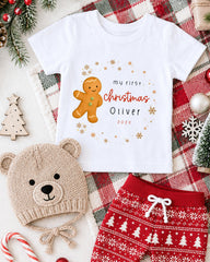 A white t-shirt with a gingerbread man graphic and text, a beige knit hat, red and white patterned shorts, and Christmas decorations such as a tree, candy canes, and snowflakes.